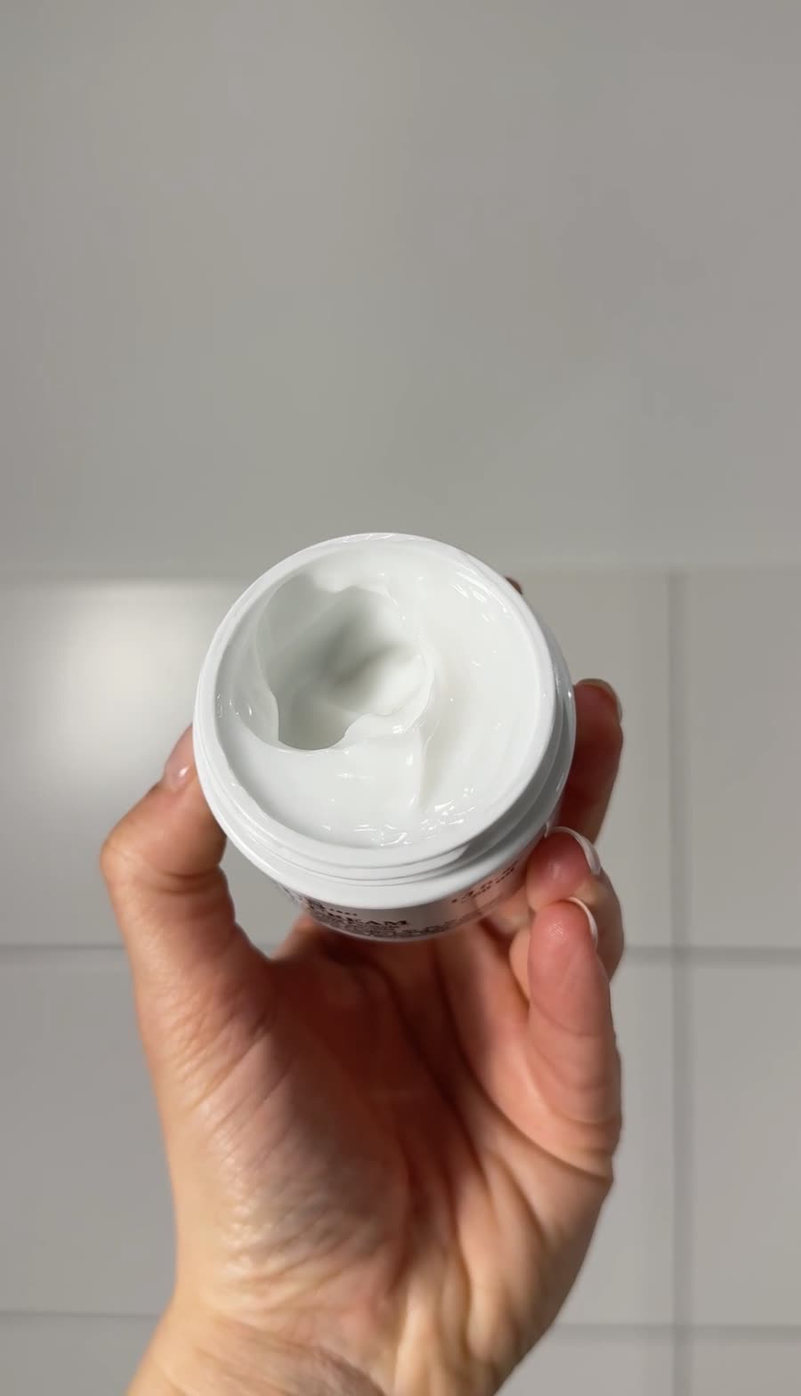 Geöffneter Cremetiegel in der Hand